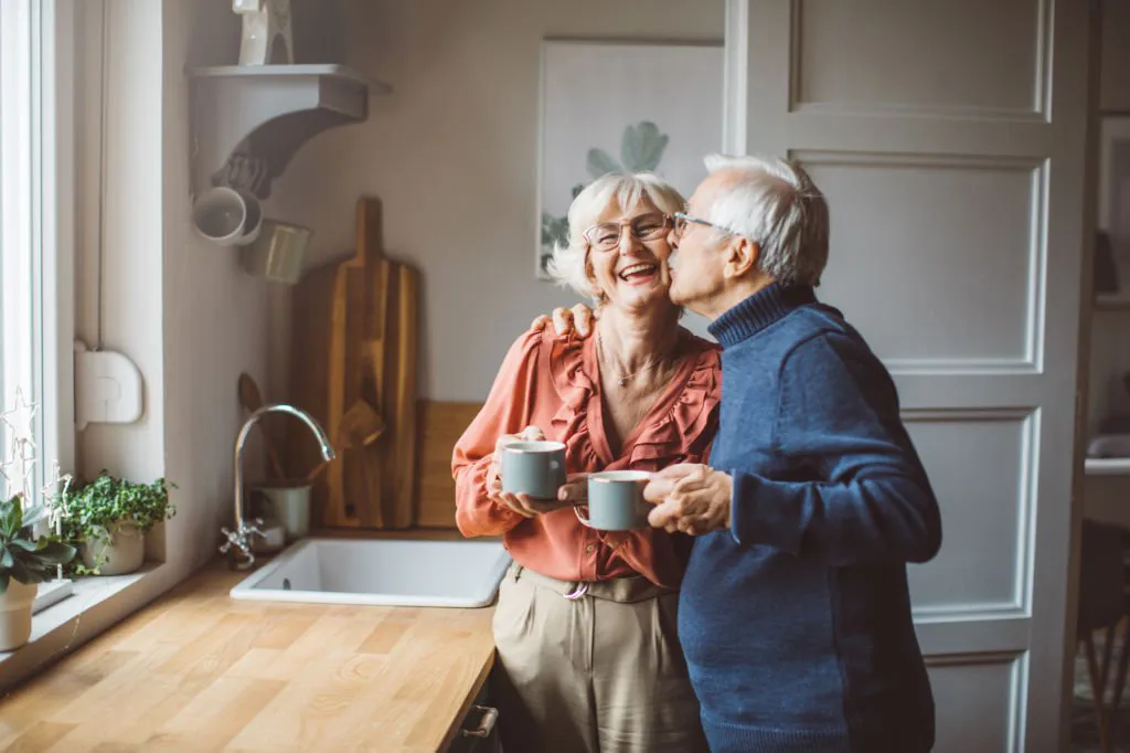 Older couple kissing in kitchen