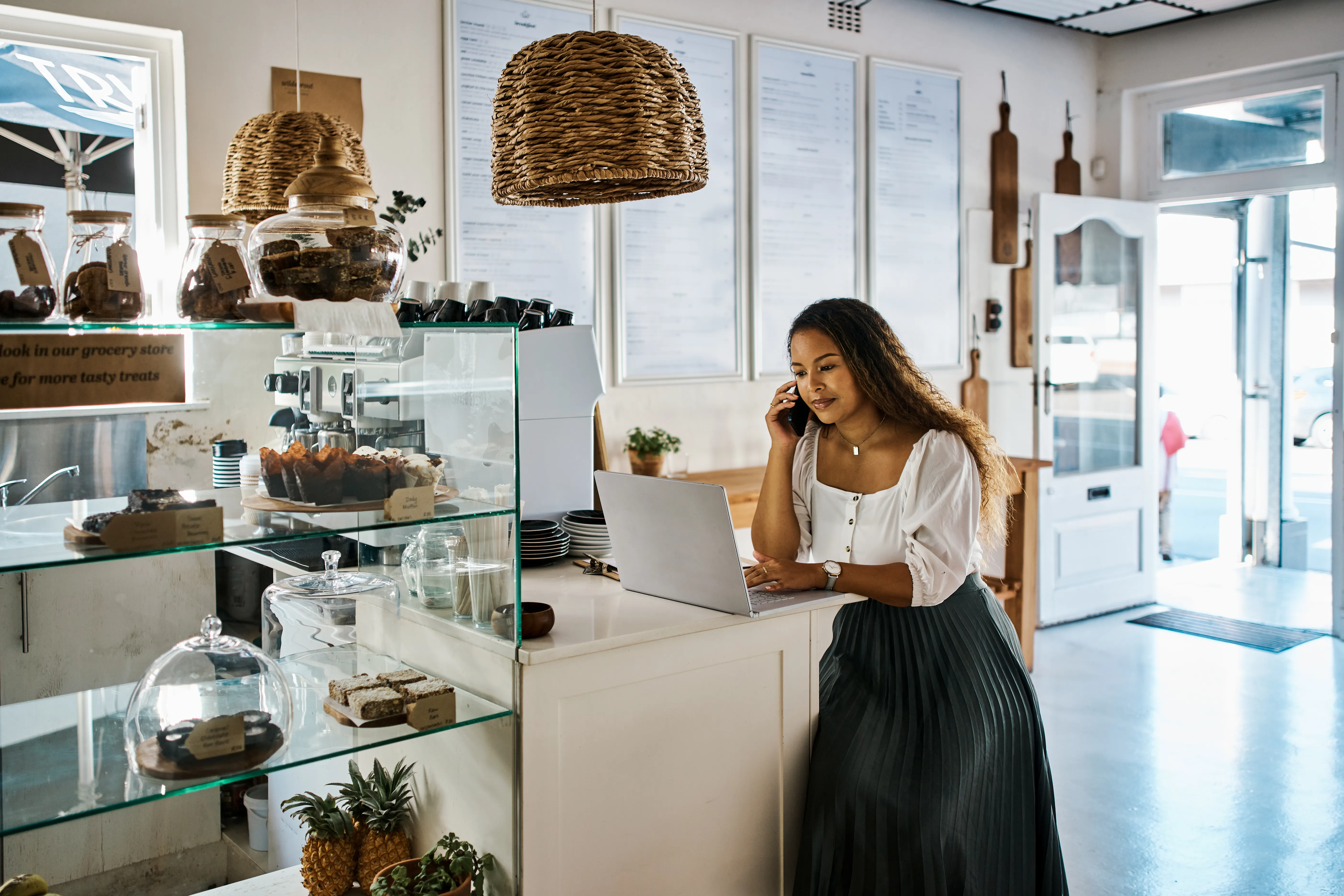 Entrepreneur talking on a phone and laptop in a trendy bakery shop